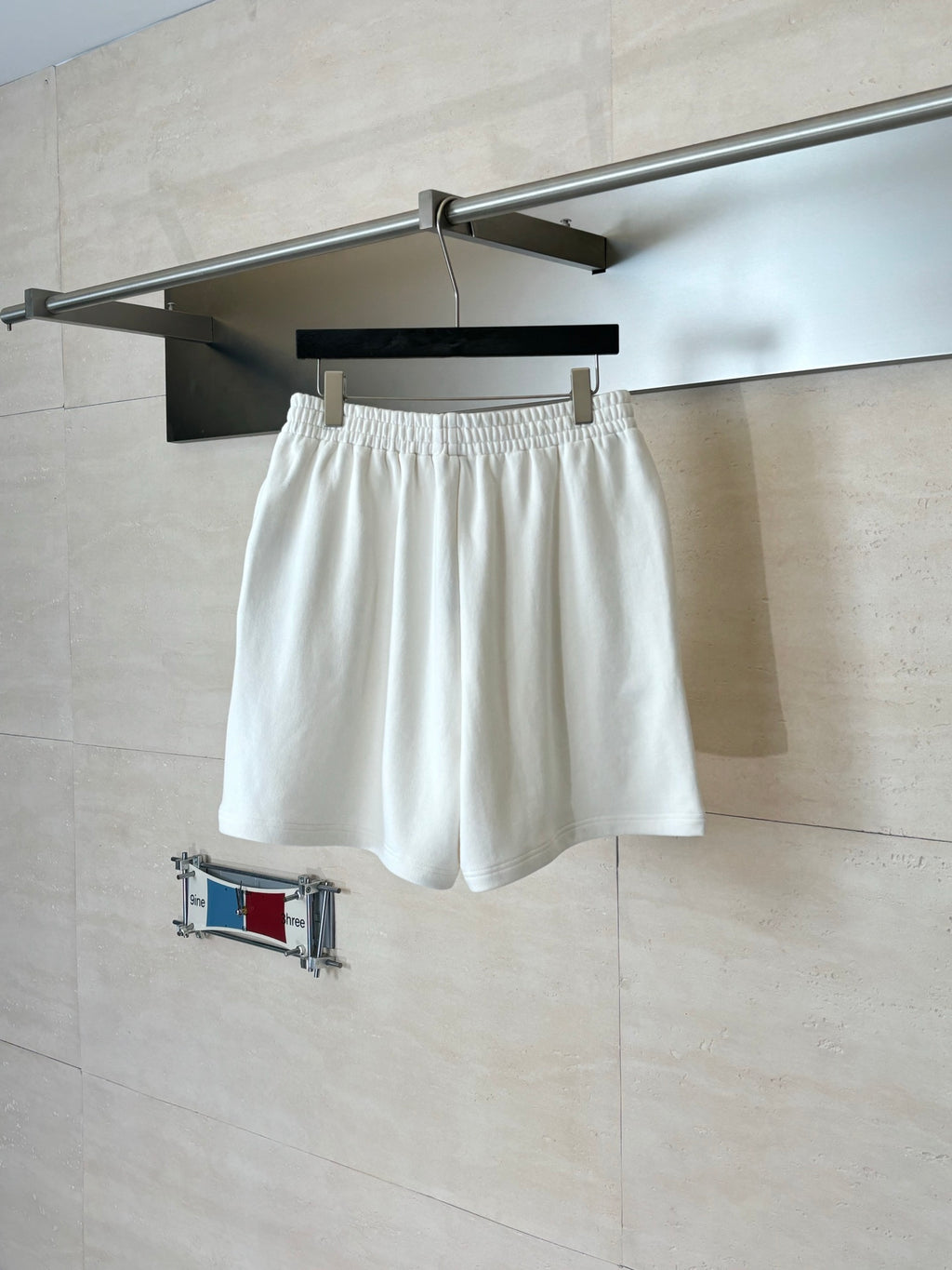 White Balenciaga shorts on hanger; navy shorts partially visible behind.