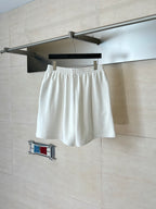 White Balenciaga shorts on hanger; navy shorts partially visible behind.