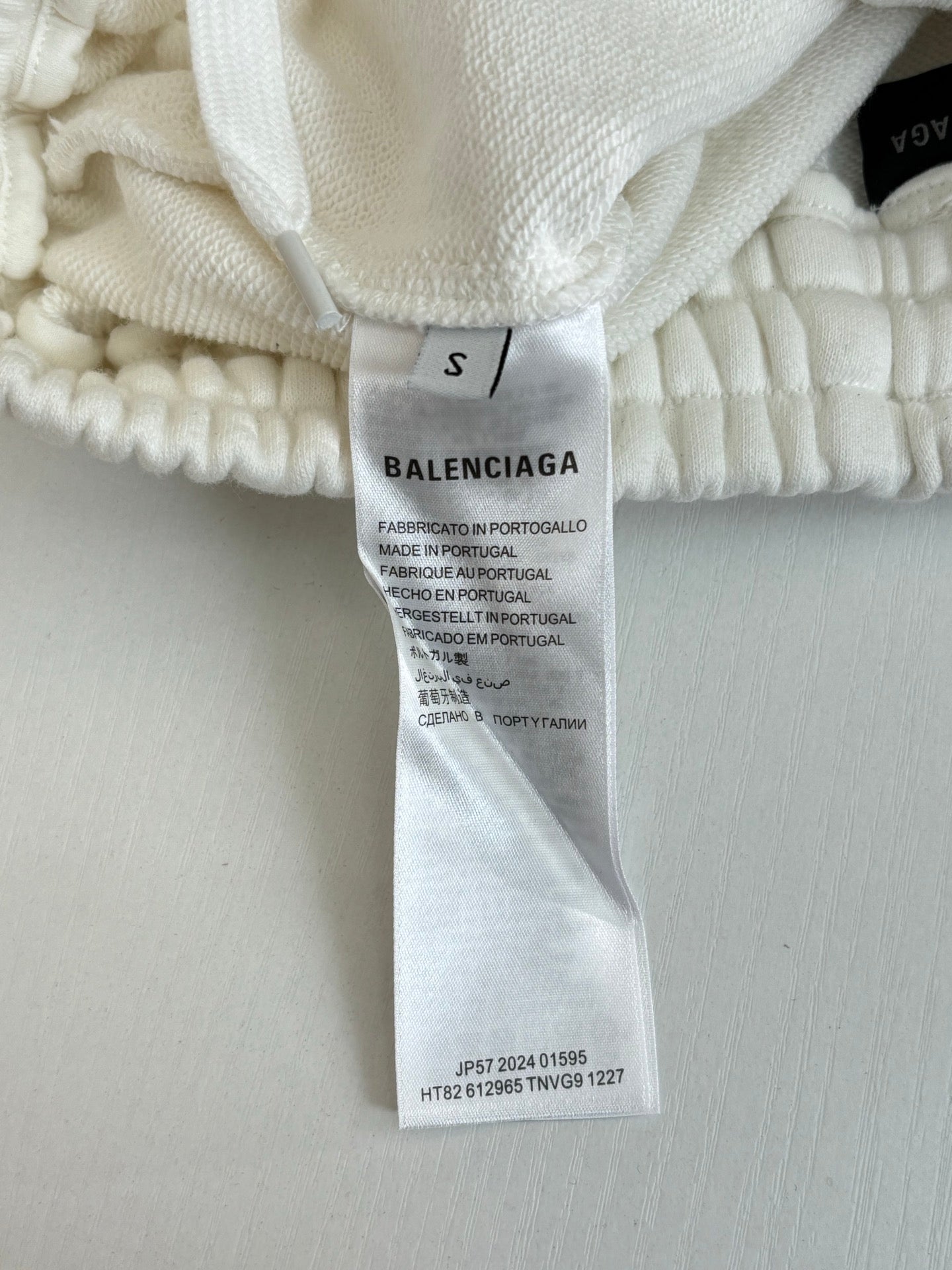 Balenciaga size S fabric tag on white shorts waistband, with product info text.