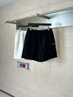 Black shorts on a hanger with elastic waistband; matching white shorts shown behind