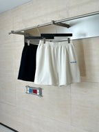 White Balenciaga shorts on hanger with elastic waistband; dark shorts partially visible behind.