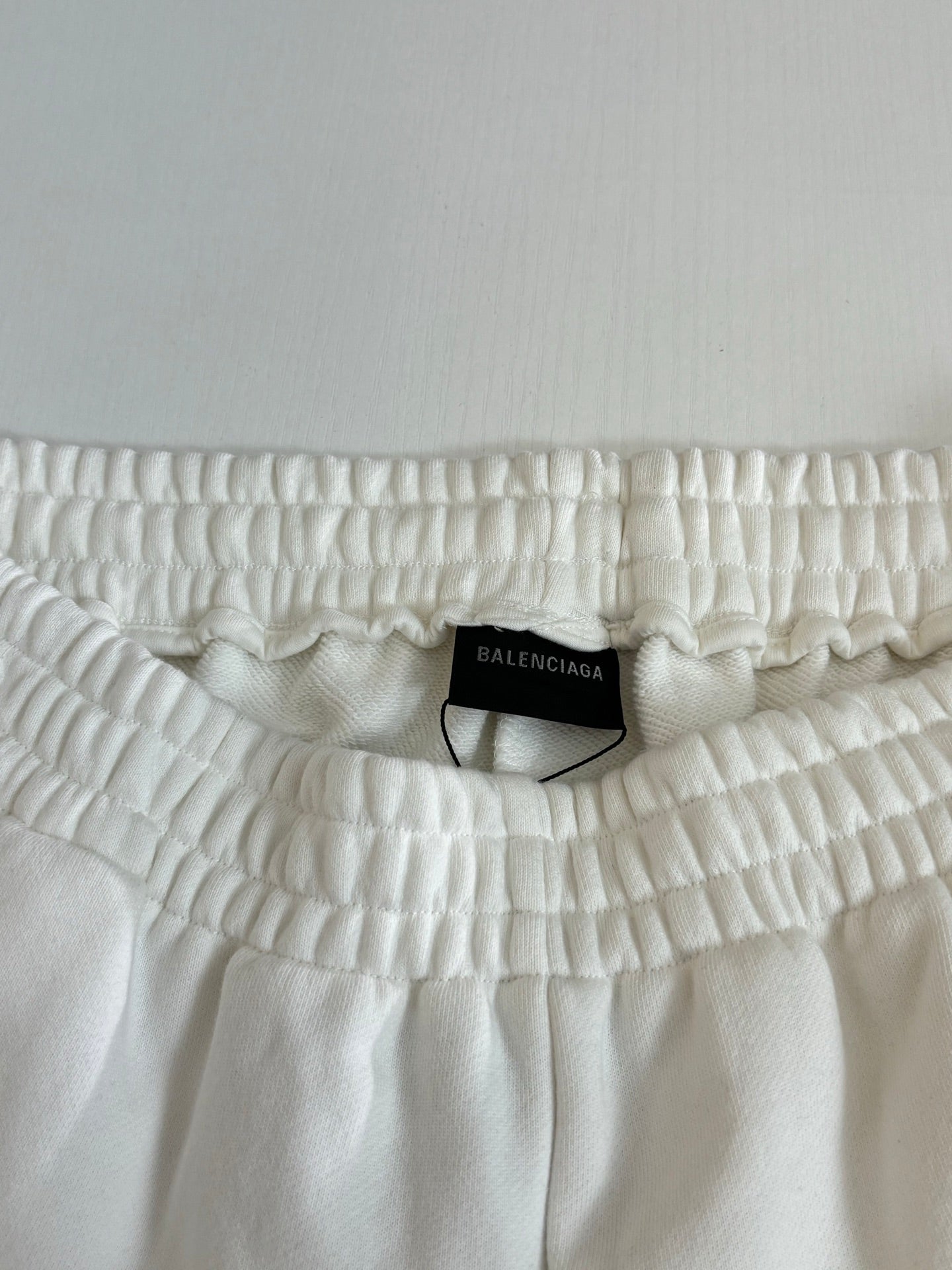 White Balenciaga shorts waistband close-up with gathered elastic and size tag label.