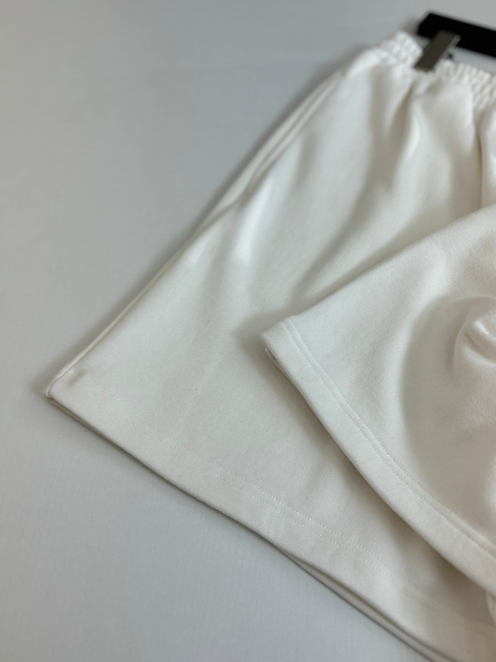 White Balenciaga shorts folded, showing elastic waistband and relaxed leg openings.