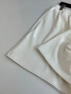 White Balenciaga shorts folded, showing elastic waistband and relaxed leg openings.