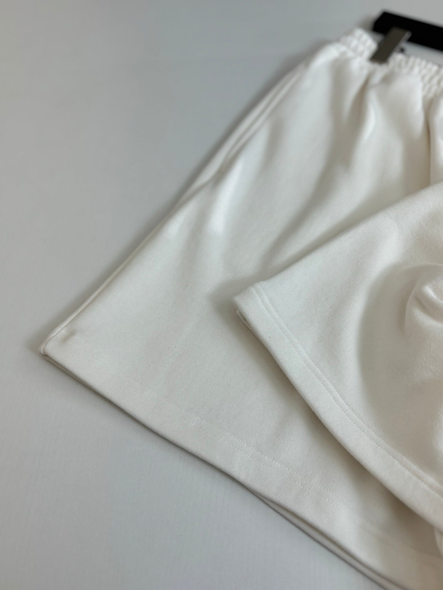 White Balenciaga shorts folded, showing elastic waistband and relaxed leg openings.