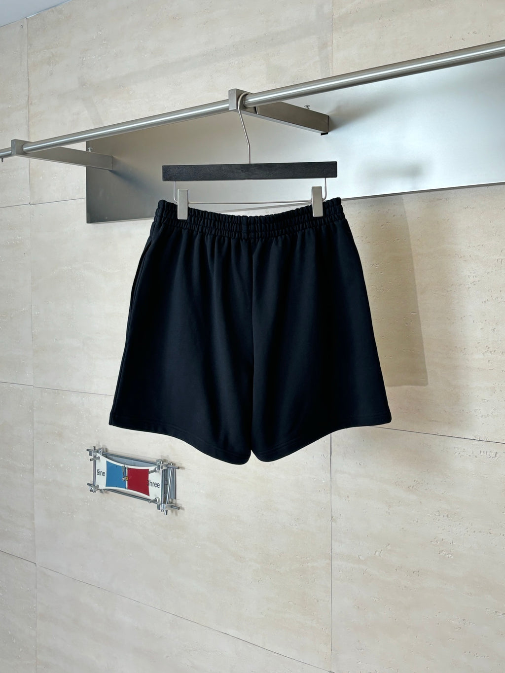 Black elastic-waist shorts on a hanger, with a small BALENCIAGA logo on the front
