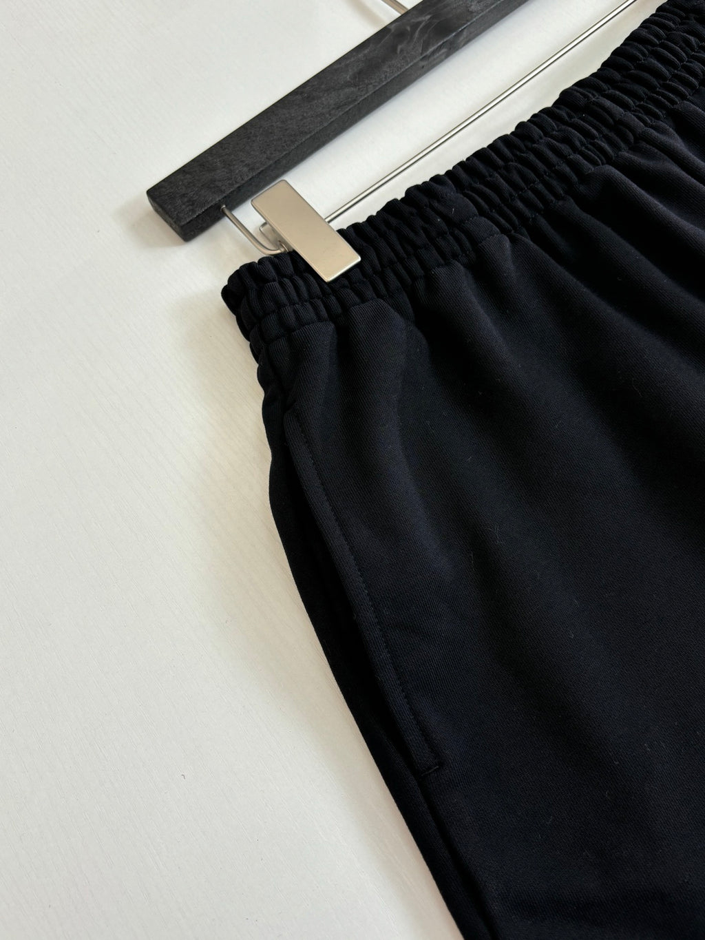 Black shorts detail showing elastic waist and textured fabric; hanging label at top