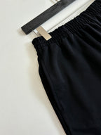 Black shorts detail showing elastic waist and textured fabric; hanging label at top
