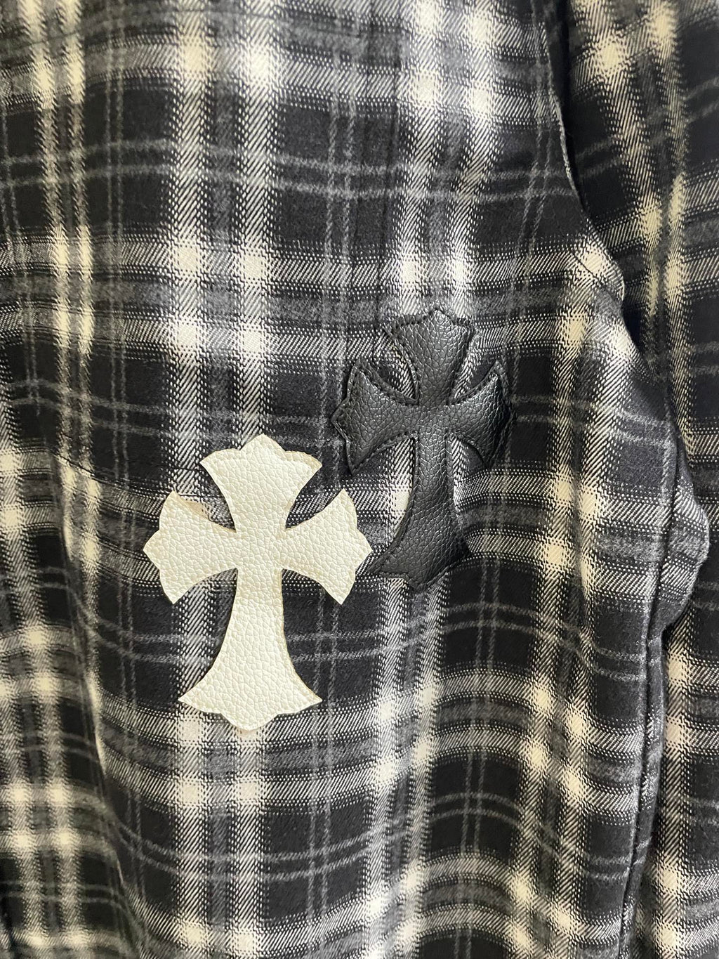 Detail view of black-and-white plaid fabric with white cross applique patch
