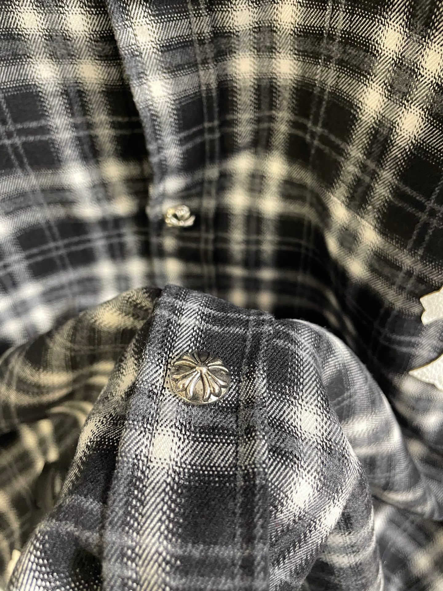 Close-up of plaid button area with decorative metal button on garment