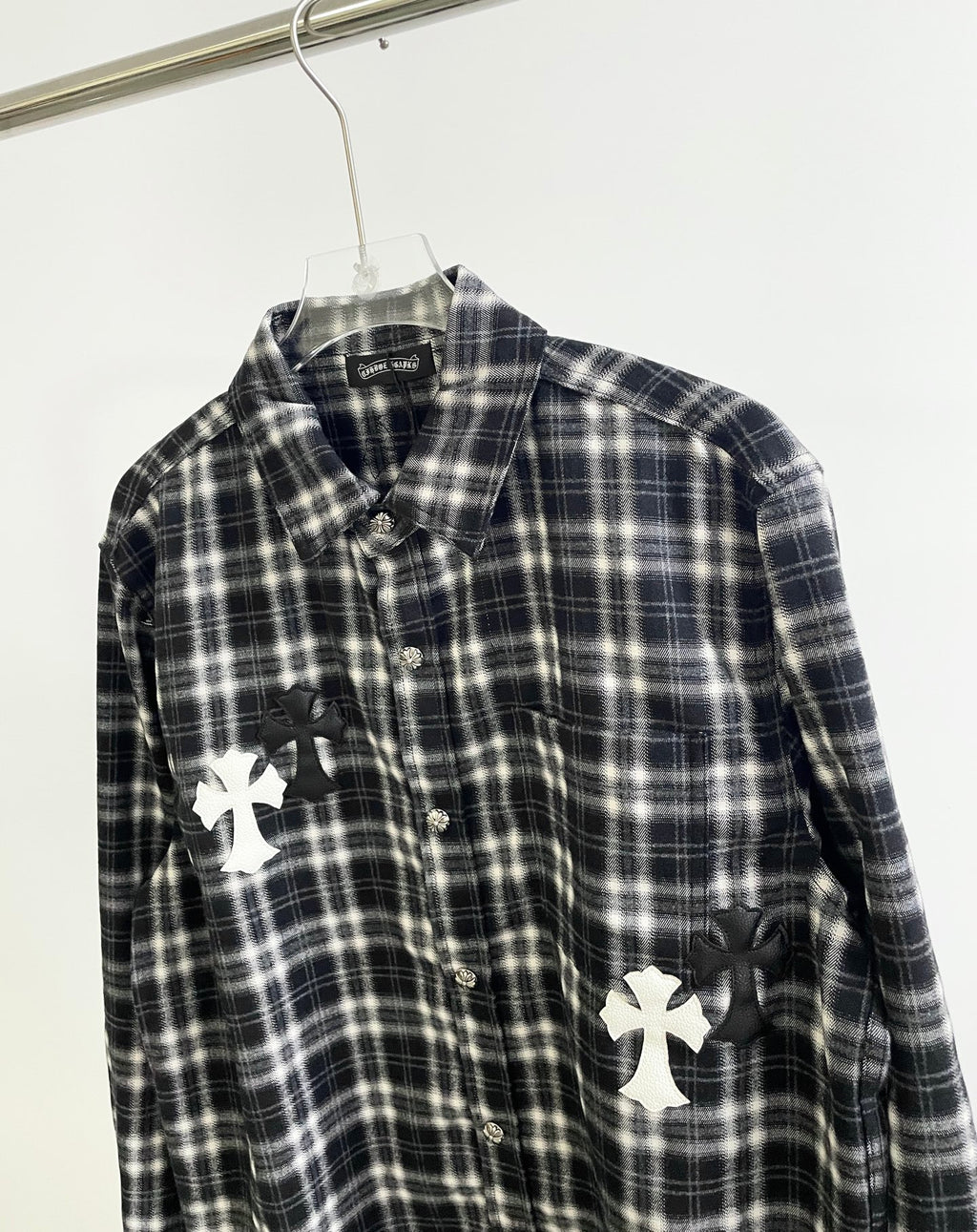 Close-up of black and white plaid button-up with white cross appliques on front