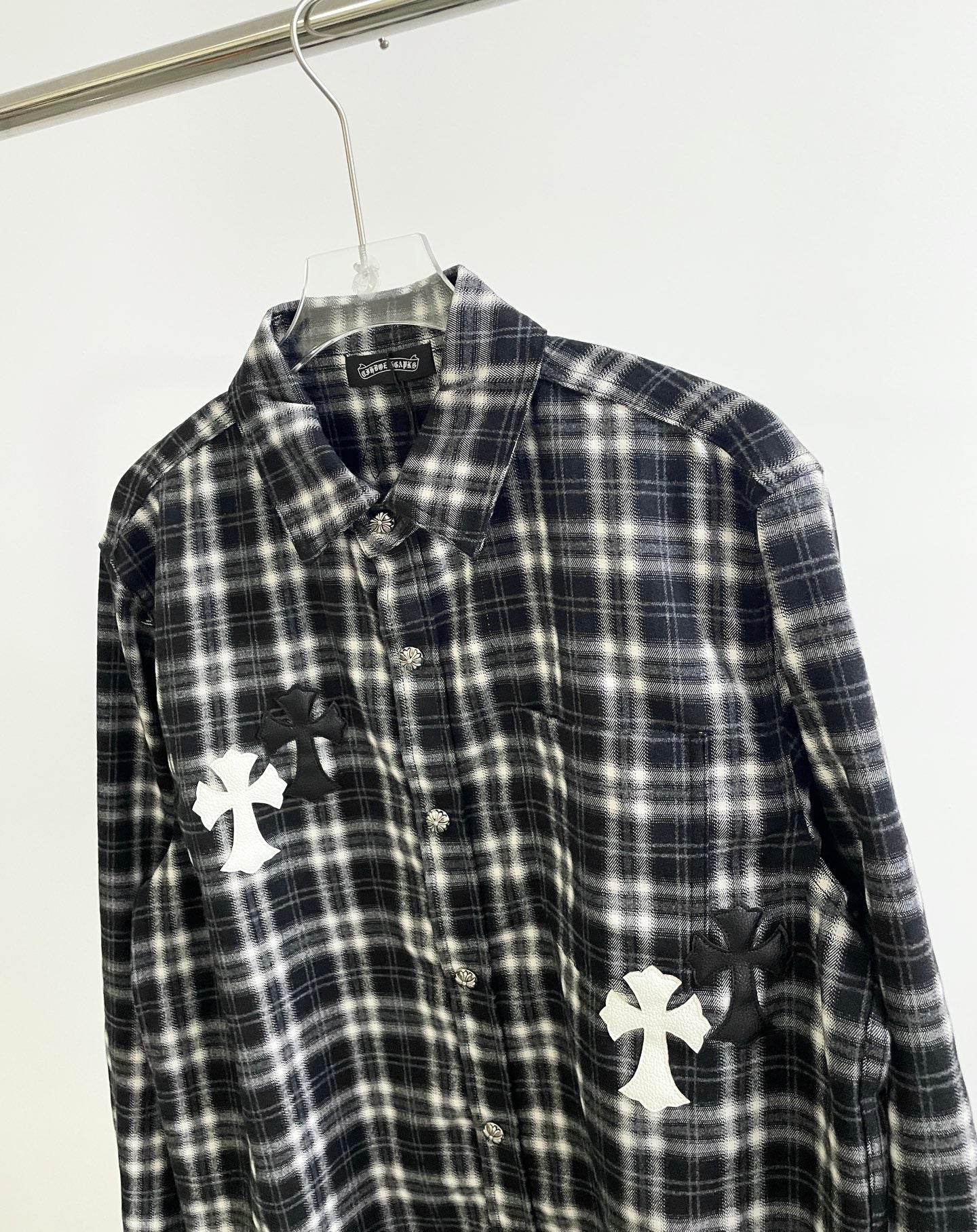 Close-up of black and white plaid button-up with white cross appliques on front