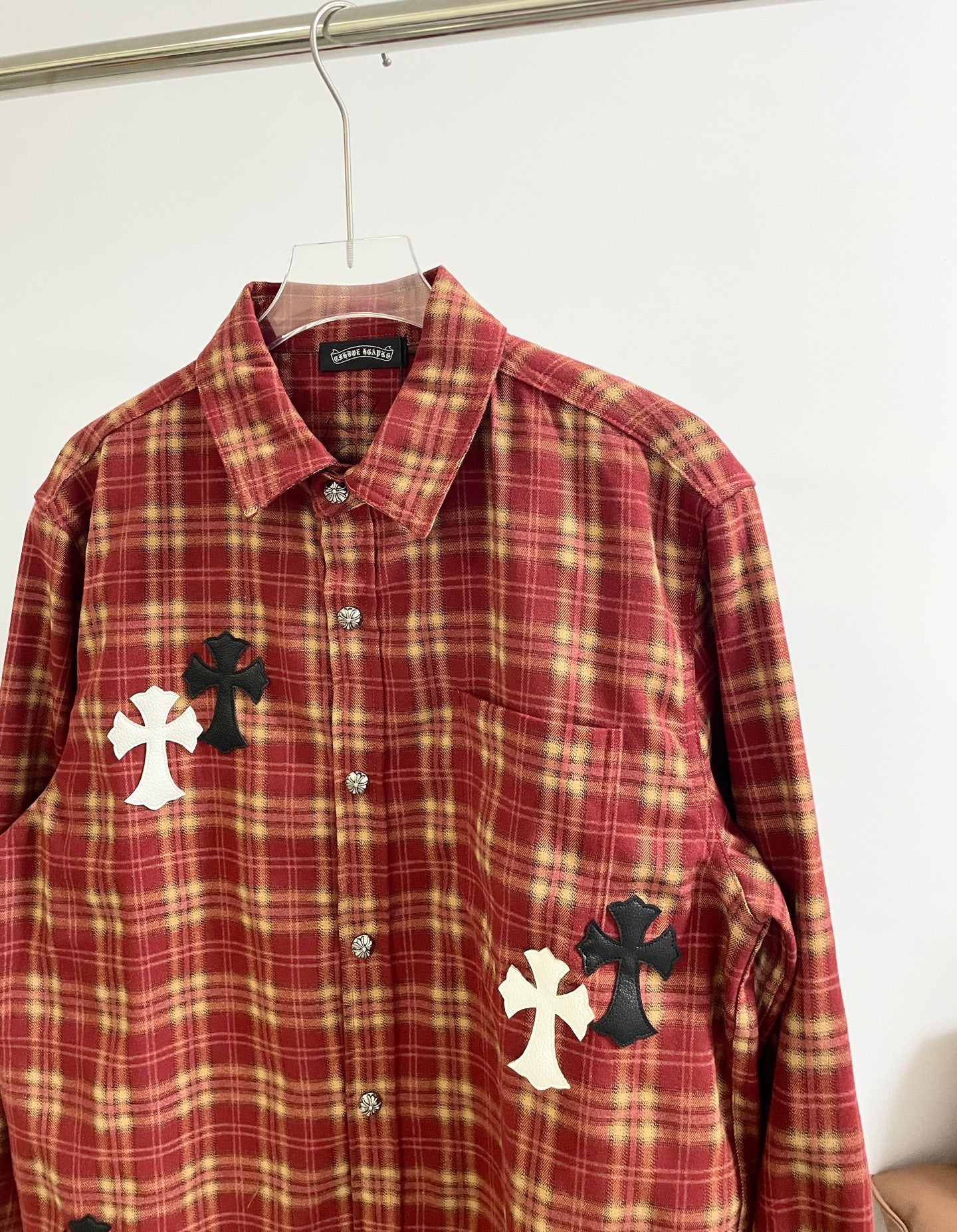 Red plaid long-sleeve shirt front with button placket and large cross patch