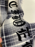 Blue plaid shirt sleeve with black embroidered graphic motifs
