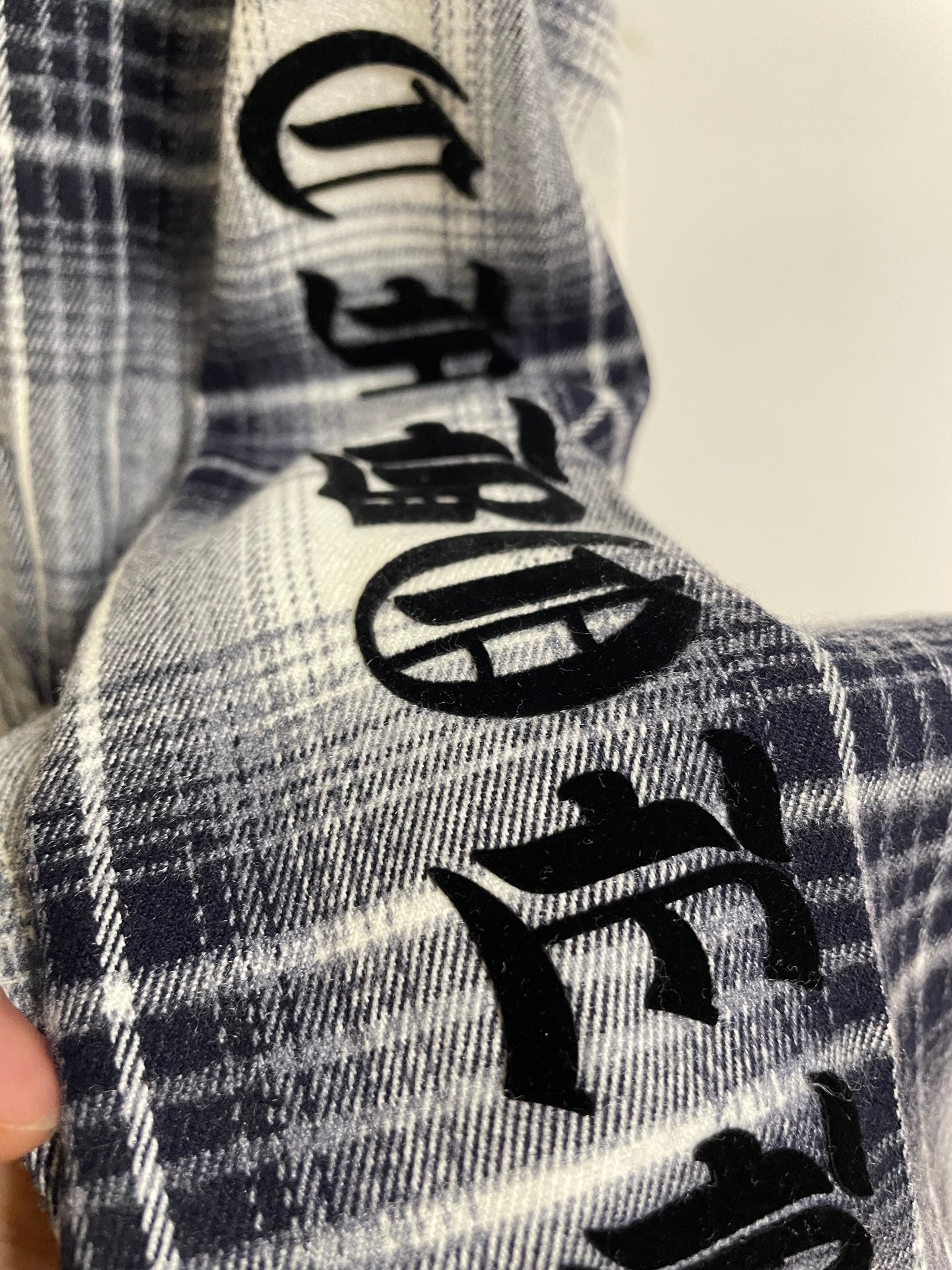 Blue plaid shirt sleeve with black embroidered graphic motifs