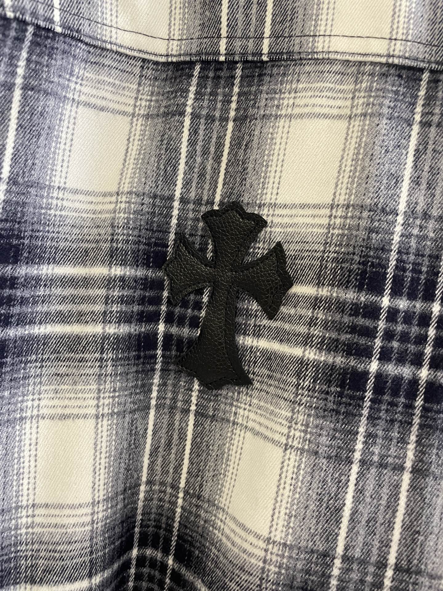 Blue and white plaid fabric with black embroidered cross-like motif