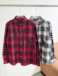 Red plaid button-up shirt with long sleeves and black embroidered motifs