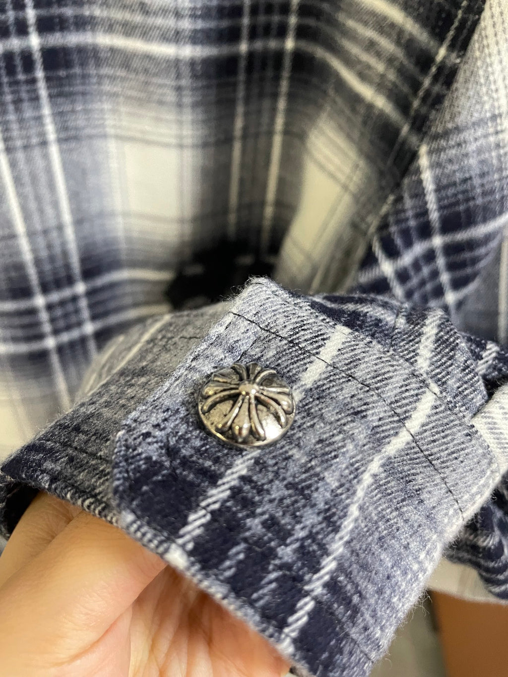 Plaid shirt cuff with gold-tone button and black embroidered detail