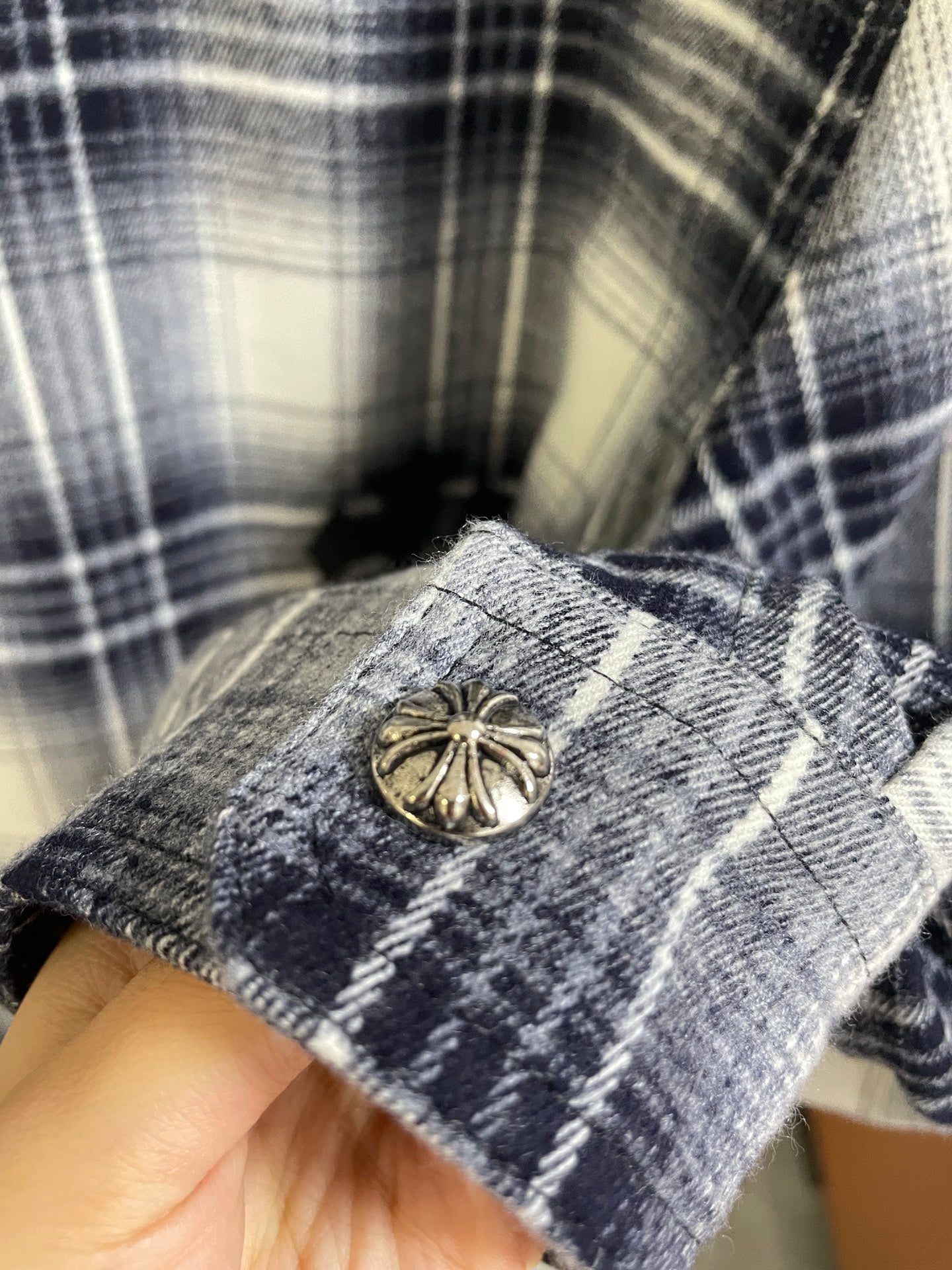 Plaid shirt cuff with gold-tone button and black embroidered detail