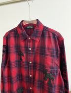 Long-sleeve red plaid shirt front with button placket and dark embroidered patches