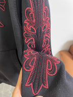 Dark hoodie sleeve with red ornamental embroidery motif