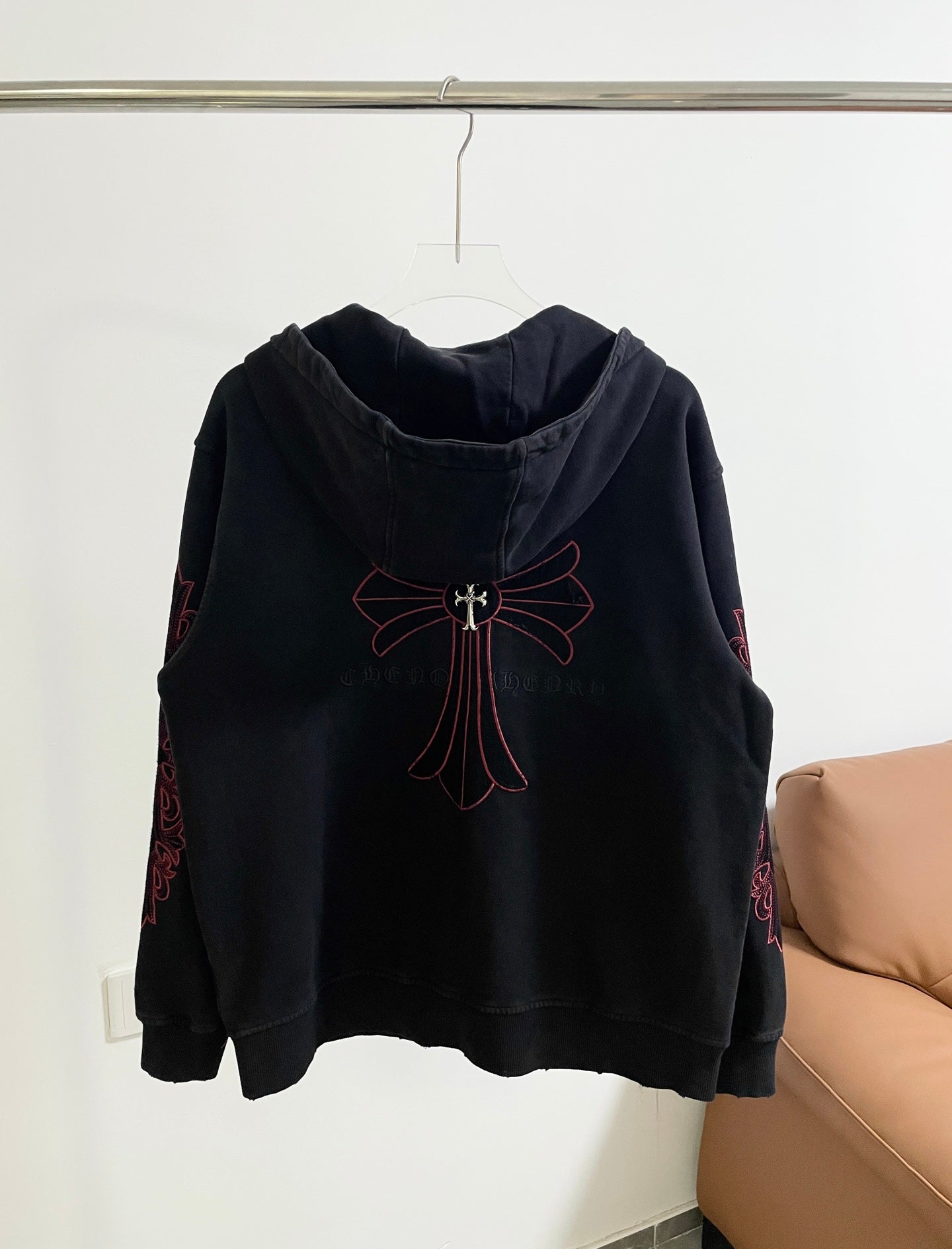 Dark hoodie with hood and large red cross-bow emblem on upper back