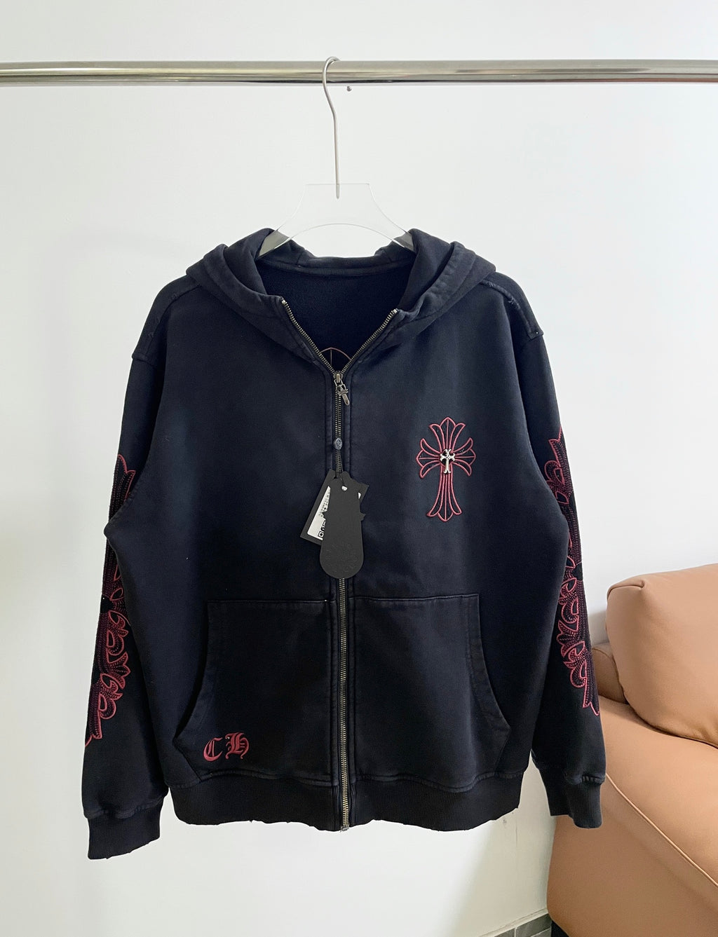 Dark zip-up hoodie with hood and front cross emblem in red embroidery