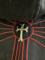 Dark hoodie cross emblem with gold center and red stitched rays