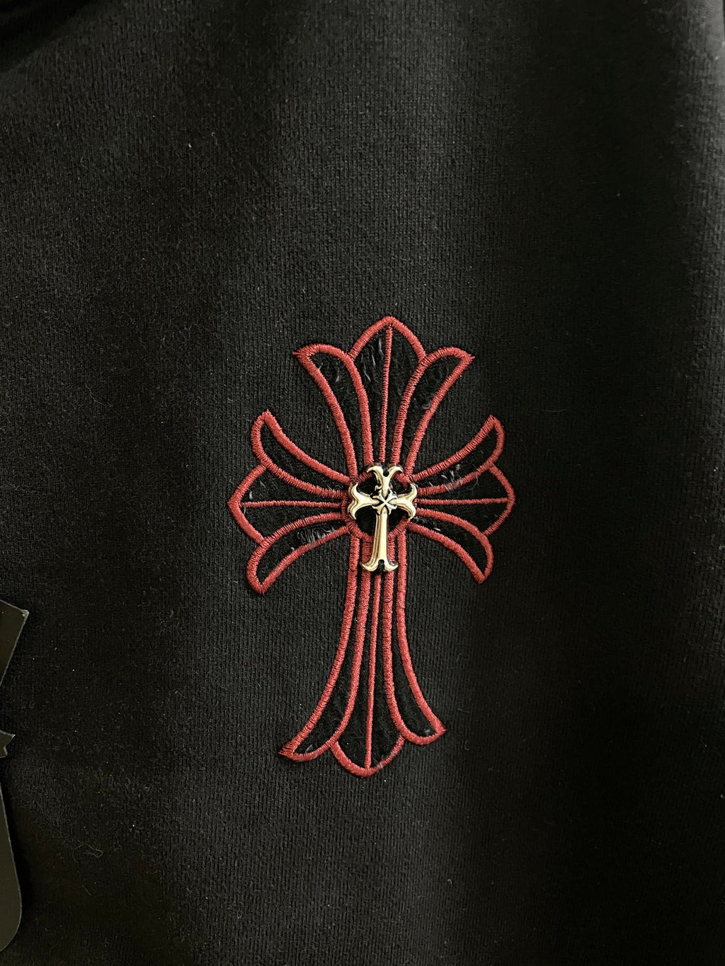 Dark hoodie with red outlined cross emblem on the chest