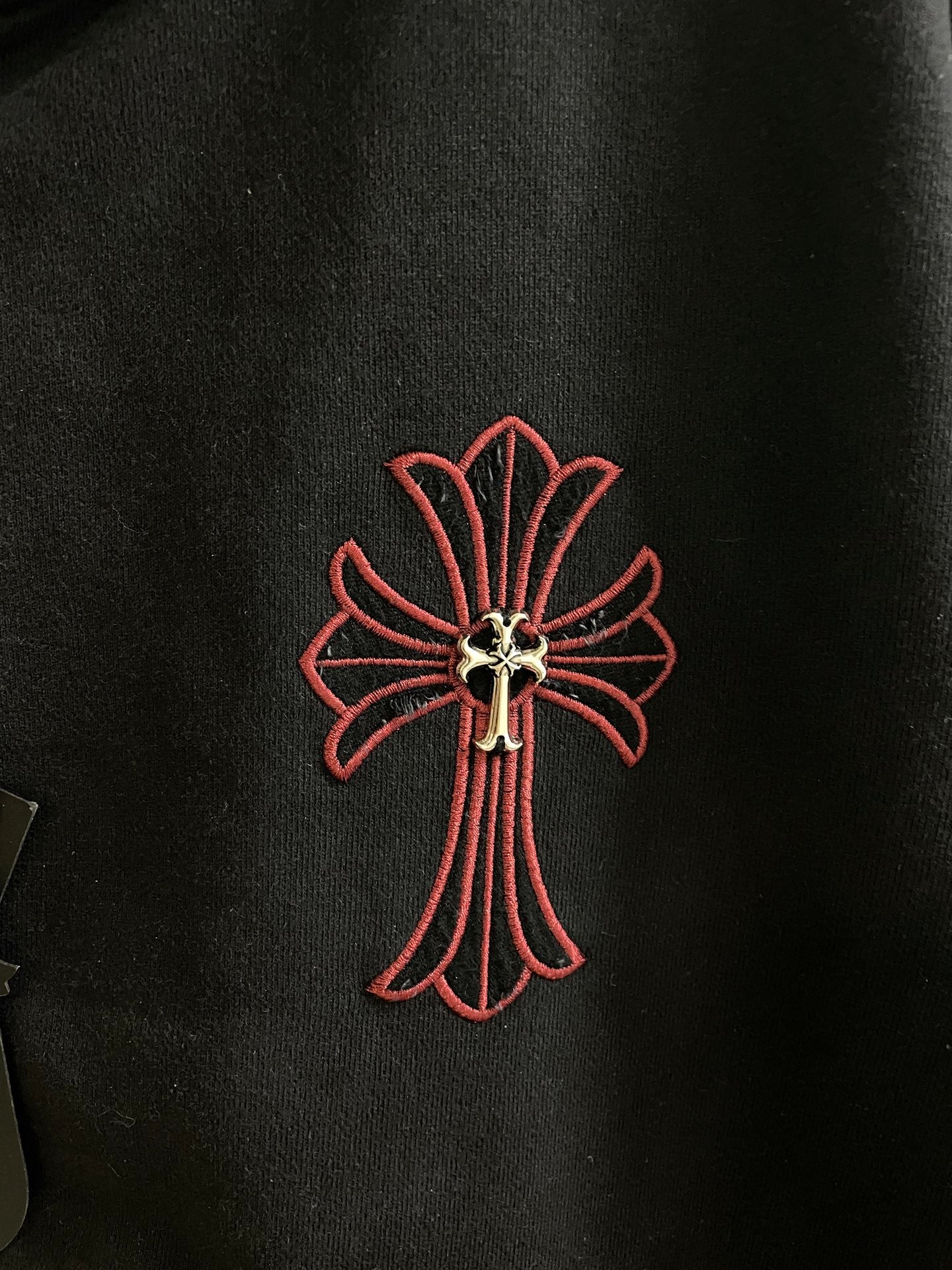 Dark hoodie with red outlined cross emblem on the chest