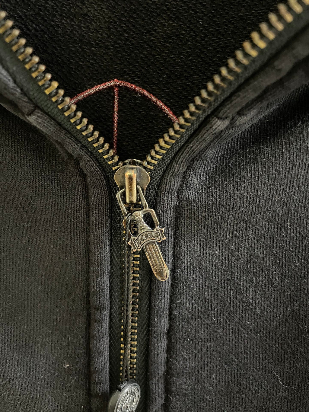 Dark hoodie zipper with gold-tone pull and black fabric placket