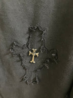 Close-up of dark fabric with stitched cross graphic and small embroidered accents