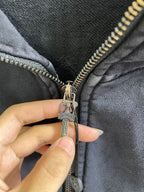 Close-up of zipper pull on dark hoodie with metal charm and engraved hardware