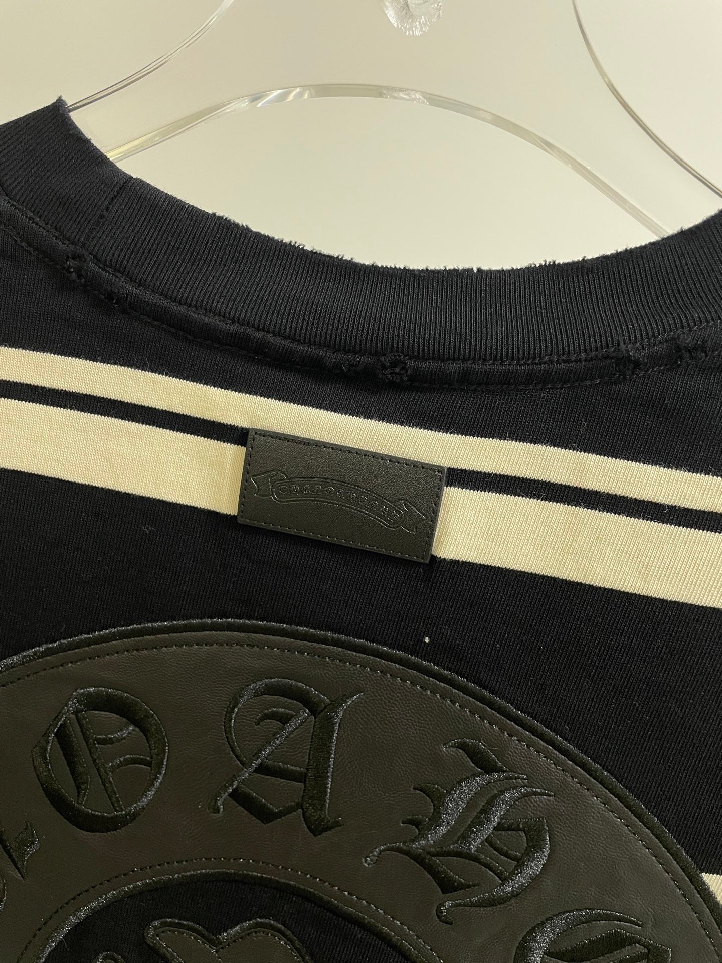 Navy striped long-sleeve shirt with woven label at neckline and textured crest patch