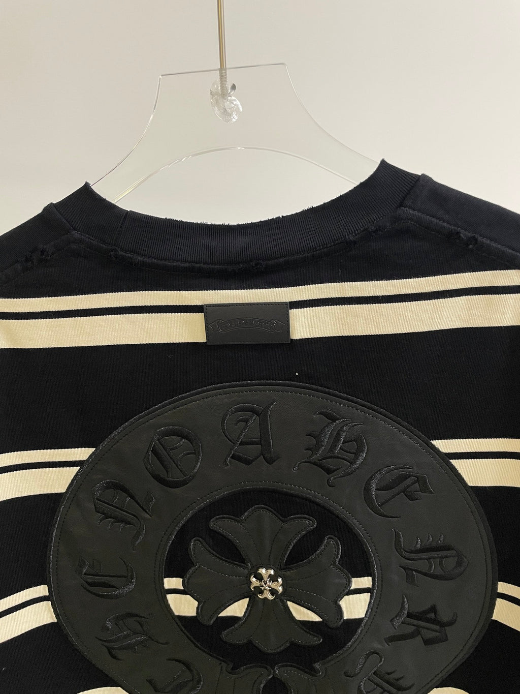 Close-up of large dark circular crest patch on navy striped long-sleeve shirt