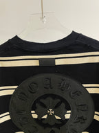 Close-up of large dark circular crest patch on navy striped long-sleeve shirt