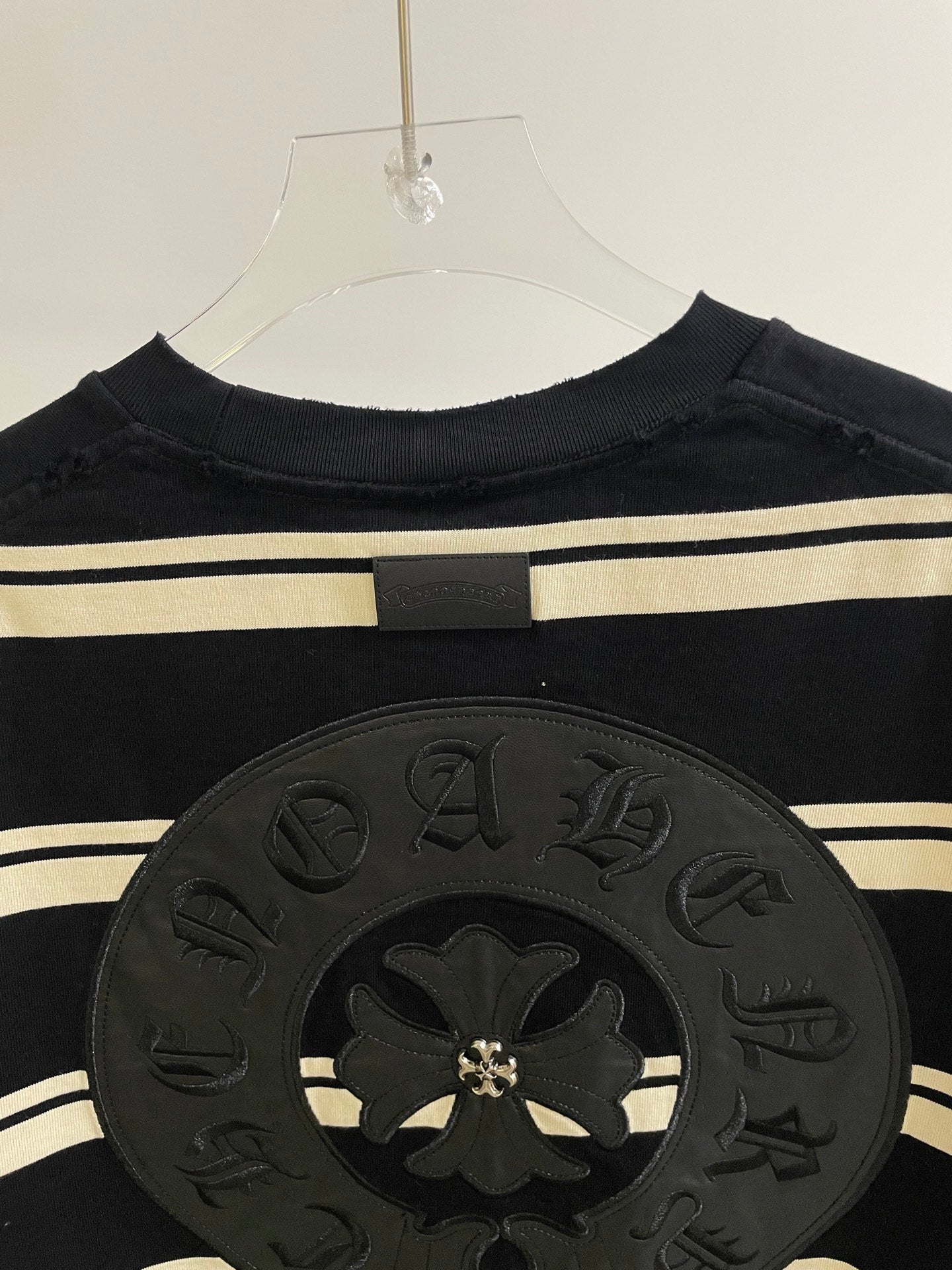 Close-up of large dark circular crest patch on navy striped long-sleeve shirt