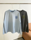 Light blue long-sleeve T-shirt, crew neck, small blue circular chest graphic.
