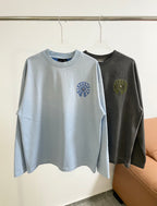 Light blue long-sleeve T-shirt, crew neck, small blue circular chest graphic.