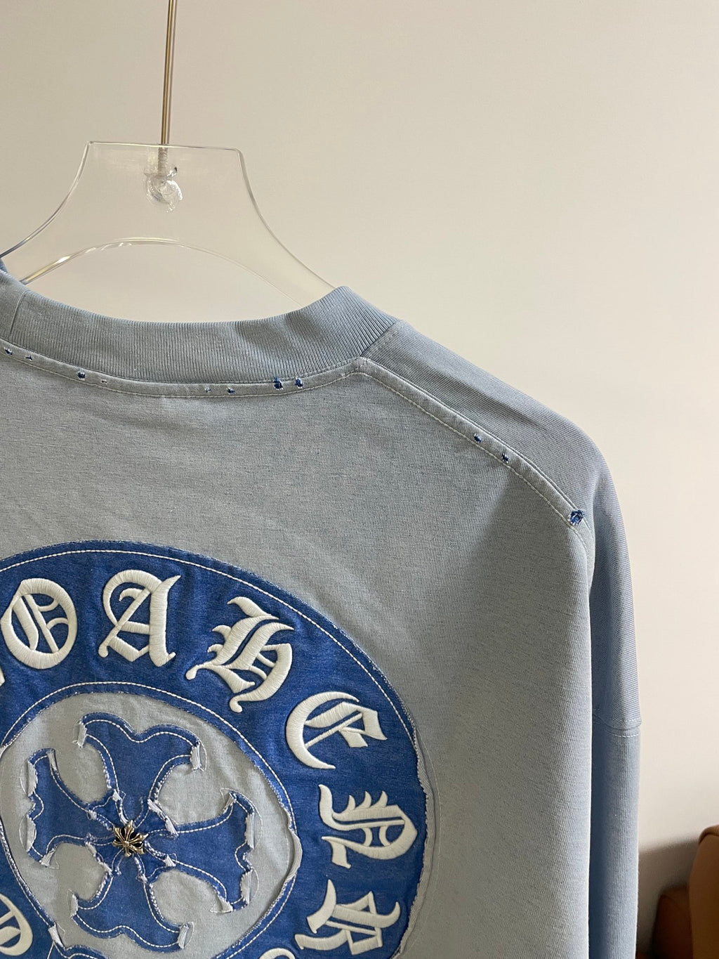 Back view of light blue long-sleeve shirt with blue embroidered circular shoulder logo
