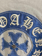 Blue circular crest on a light garment, detailed decorative letters and emblem.