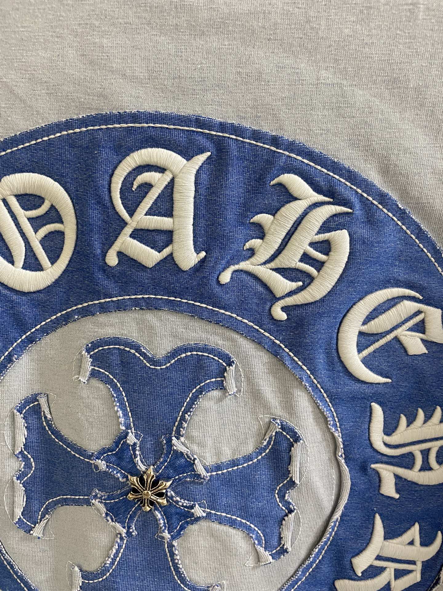 Blue circular crest on a light garment, detailed decorative letters and emblem.