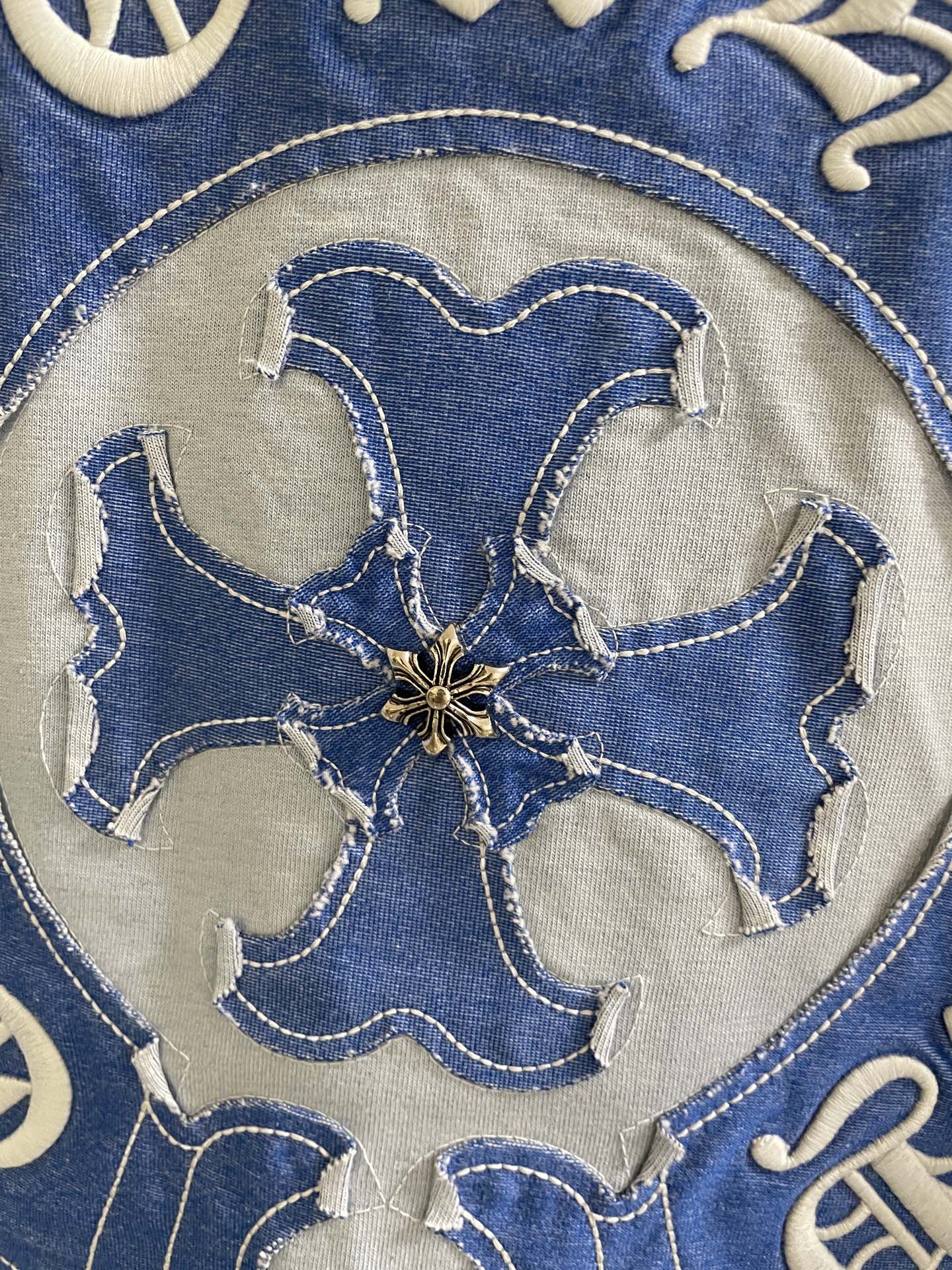 Close-up of blue embroidered flower-shaped elephant-style head on shirt logo