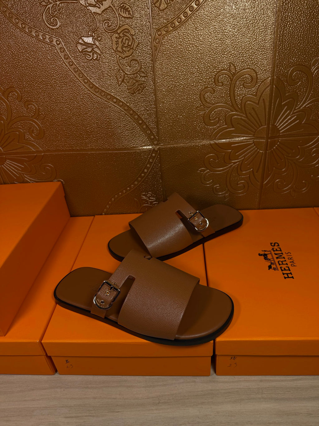 Brown leather slide sandals with two straps and silver buckle, pair on display