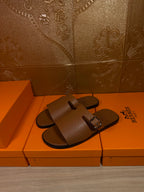 Brown leather slide sandals with double straps and silver buckle, shown from side