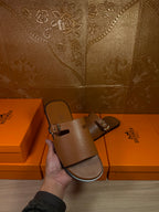 Brown leather slide sandals with silver buckle hardware on wide double straps