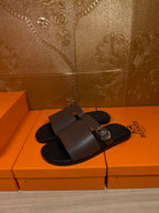 Dark brown slide sandals with single wide strap and silver buckle detail