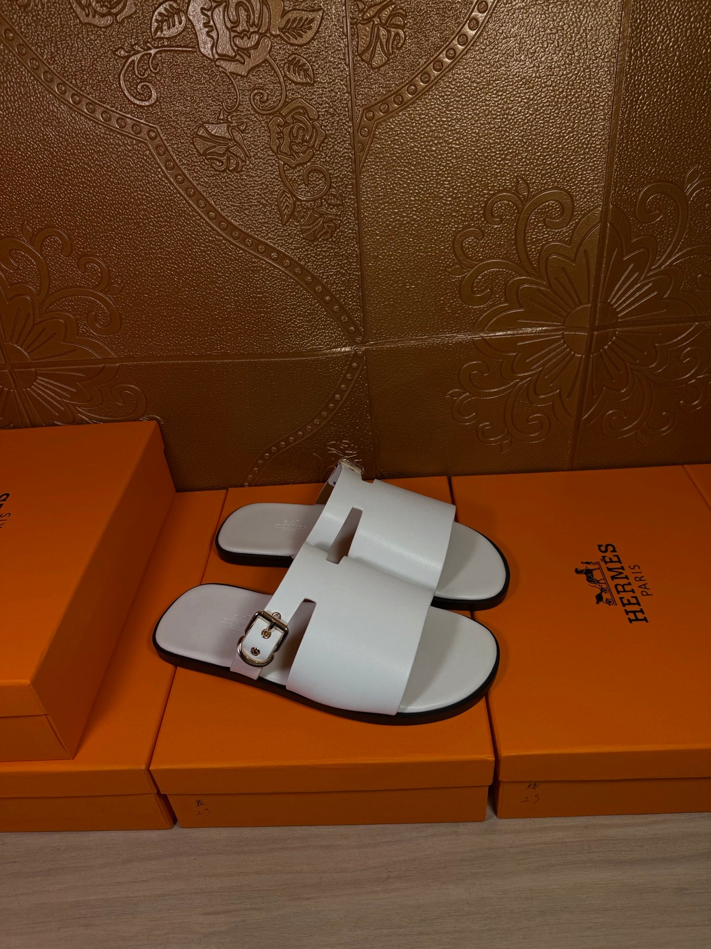 White slide sandals with two buckled straps, flat open-toe footbed
