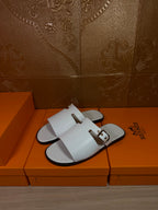 White slide sandals with front strap and side buckle, flat open-toe sole