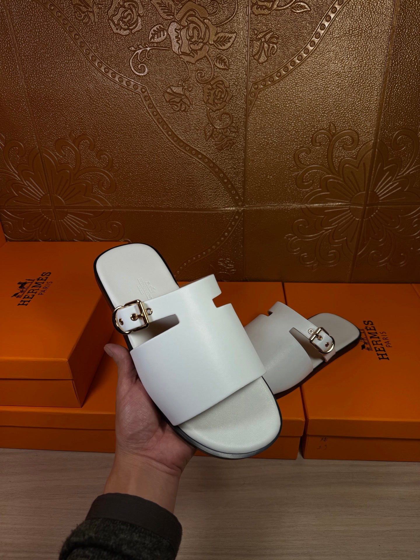 White slide sandal in hand, open toe with double straps and metal buckles